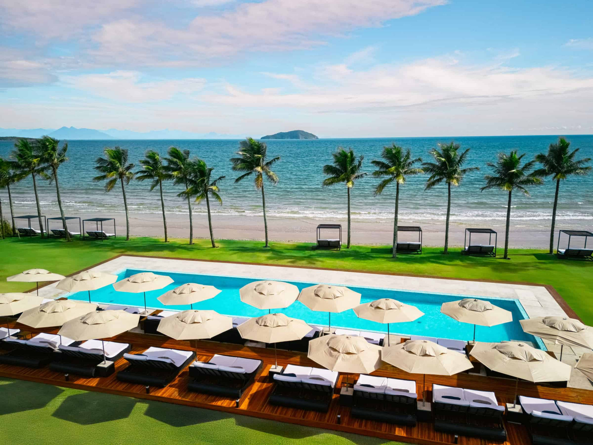 Beachfront pool with lounge chairs and palmtrees at Zendaya Resort in Búzios 